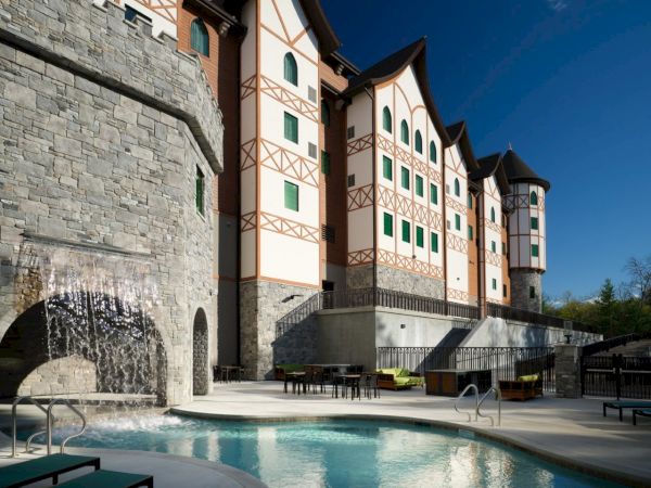A stone-and-wood hotel with peach-and-tan exterior, green-trimmed windows, a curved roofline, and a warm outdoor pool area.
