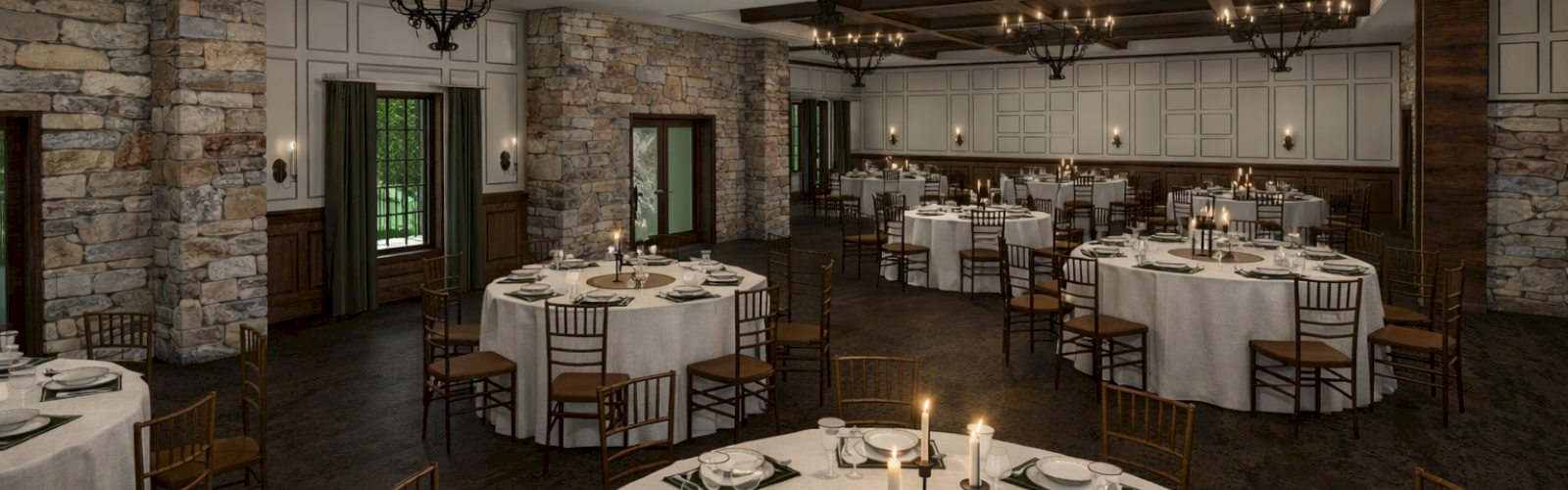 A formal dining room with stone walls, wooden beams, chandeliers, and round tables set with white linens, candles, and place settings.