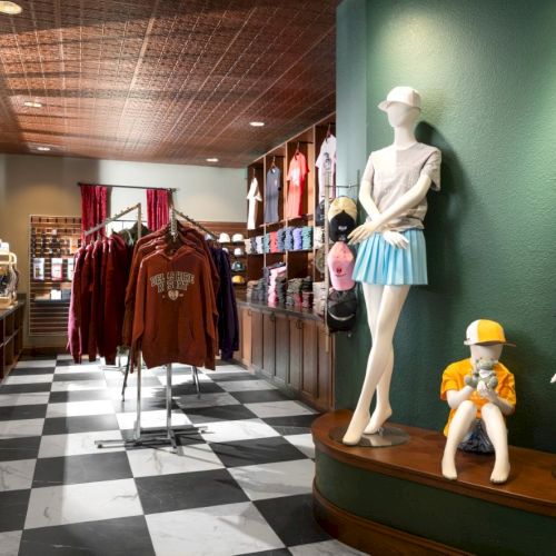 A clothing store displays trendy merch on mannequins and racks; checkered floor, bold colors, and playful toddler outfits nearby.