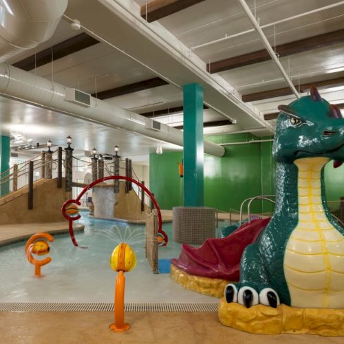 A colorful indoor playground with a dragon-shaped inflatable float at the edge of a shallow pool, kid-safe slides, and bright green walls, fun for kids.