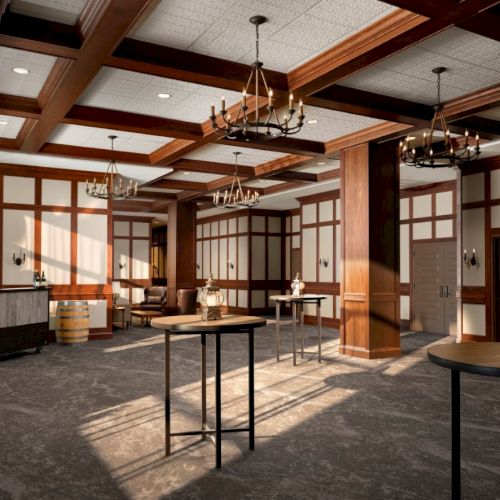 A spacious, wood-paneled event hall with chandeliers, high ceilings, cocktail tables, and a bar area along the back wall.