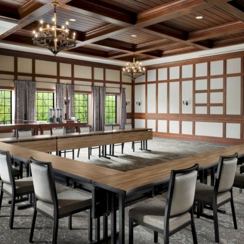 A U-shaped conference room with wood-paneled walls, long tables, and padded chairs around the perimeter, for meetings.
