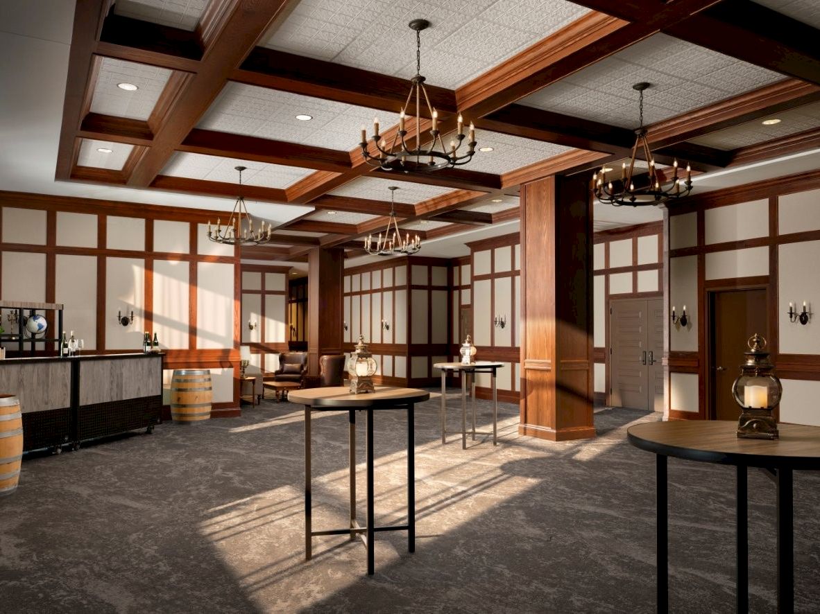 A rustic-style interior with wood paneled walls, chandeliers, high tables, and a bar area, resembling a spacious old-time saloon or tavern.