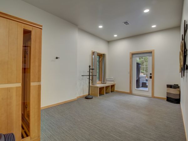Bright modern room with a carpeted floor, wooden doors, wall decor, ceiling lights, and windows with a small bench inside.