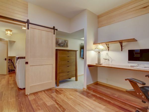 A modern room with a barn-style door, desk and lamp, and a washing machine in the adjoining laundry area.