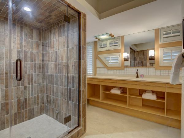 A modern bathroom with a glass walk-in shower, tiled walls, and a vanity with towels and mirrors.
