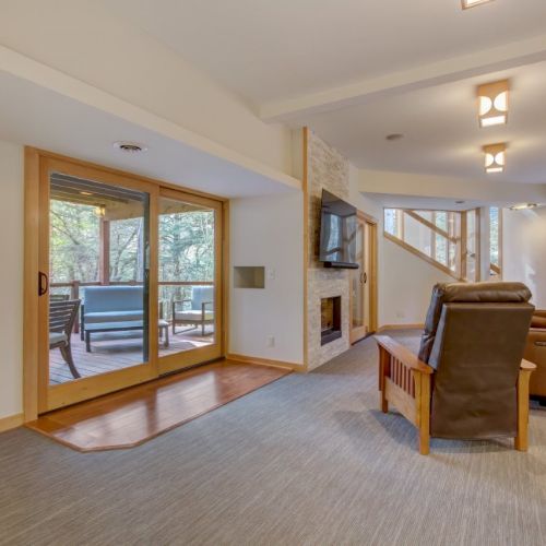 A bright living room with leather recliners, TV, wood beams, and large sliding glass doors to a patio.