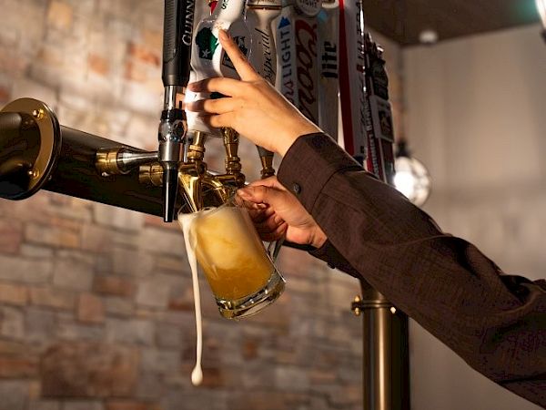 A bartender pours beer from a draft tap